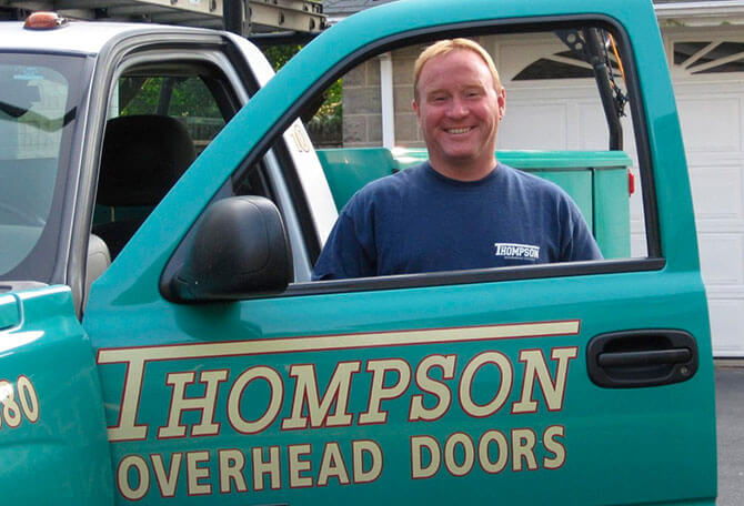 Thompson Overhead Doors expert in Natick standing next to the service truck
